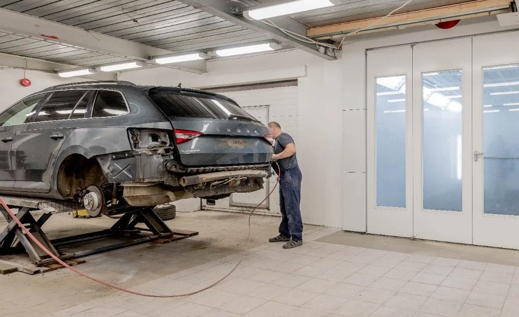 Mechanic repairing a car indoors at an auto workshop, focusing on vehicle maintenance.