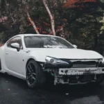white car damage in a rainy road