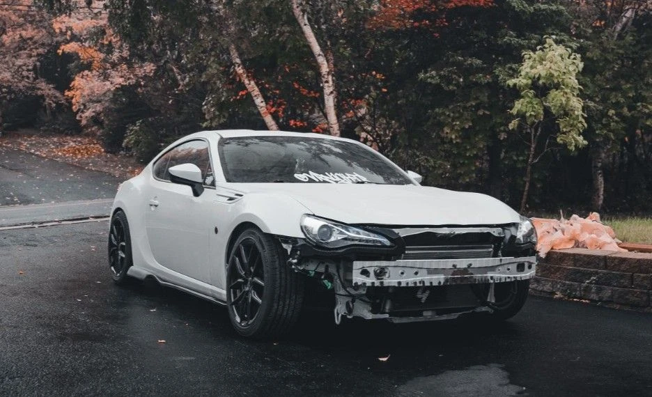 white car damage in a rainy road