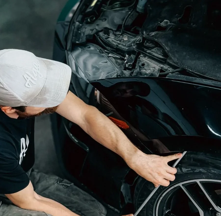 Mechanic working meticulously on a car bumper repair inside an auto garage.
