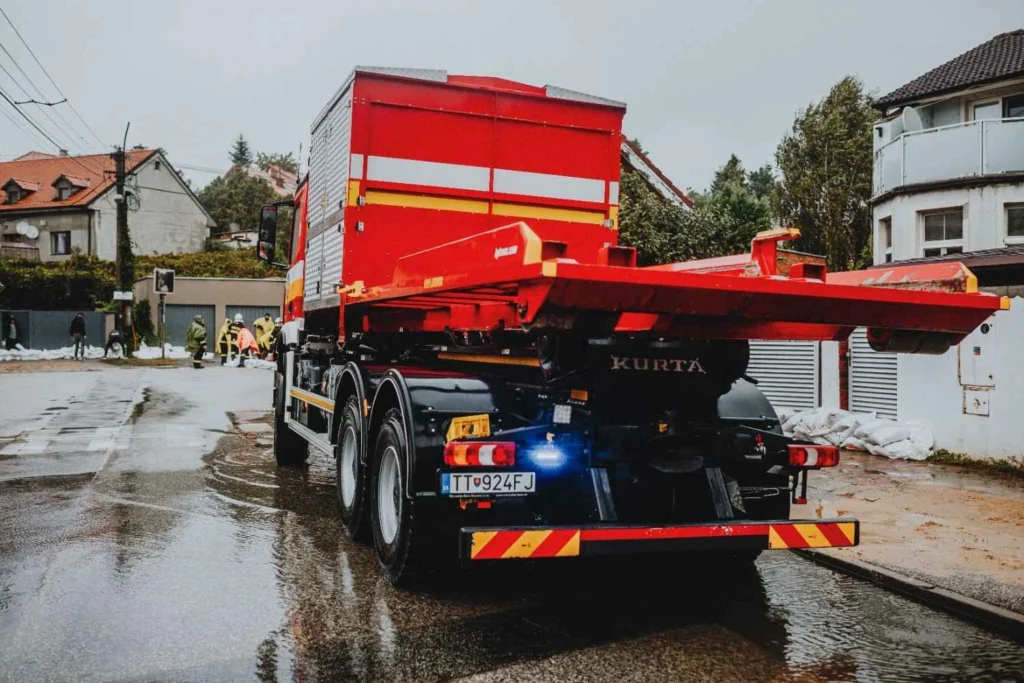 red flatbed towing truck on a rainy road