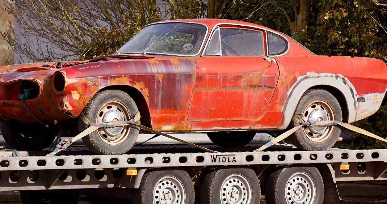 damaged old car being towed using a flatbed towing with safety precautions