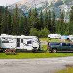 damaged rv is being towed by a black truck